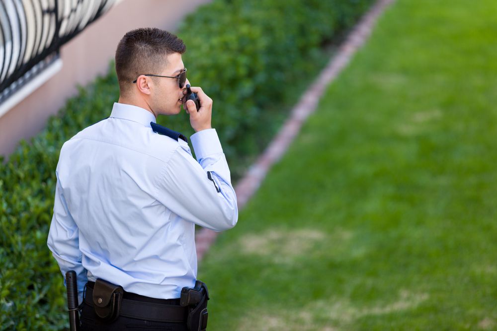 Security guard in uniform speaking into walkie talkie